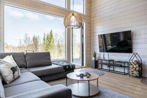 a living room with a couch and a tv at Villa Cloudberry by Hilla Villas in Kittilä