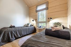 two beds in a room with wooden walls at Villa Cloudberry by Hilla Villas in Kittilä