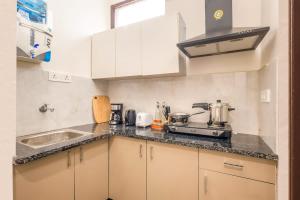 a kitchen with white cabinets and a sink at Tranquil Nest in Gurgaon with balcony in Gurgaon