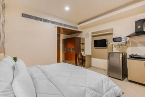 a bedroom with a large white bed and a kitchen at Eco-friendly vibes cozy space in Gurgaon