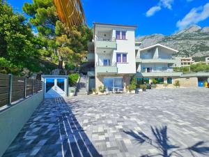un grand bâtiment blanc avec une montagne en arrière-plan dans l'établissement Apartment Tomic 2, à Makarska