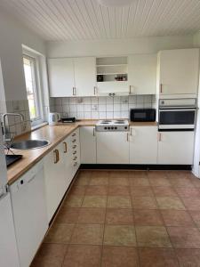 a kitchen with white cabinets and a tile floor at Joy house in Munkebo
