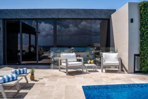 a patio with two chairs and a swimming pool at Luxury Condo en Menesse CocoBeach in Playa del Carmen