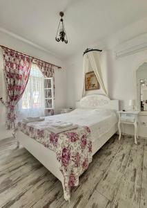 a bedroom with a large white bed and a window at Aişem By Hire in Alaçatı