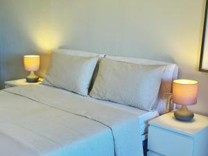 a bedroom with a white bed with two lamps on tables at VISTA MARE IN CENTRO STORICO Casa di Sara in Sciacca