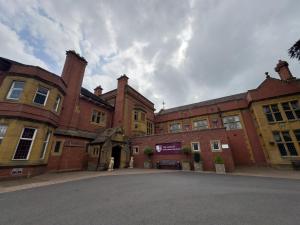 un gran edificio de ladrillo con una calle delante en The Mount Country Manor Hotel & Golf Wolverhampton, en Wolverhampton