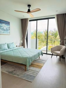 ein Schlafzimmer mit einem Bett und einem Stuhl und Fenstern in der Unterkunft Villa 95 3PN Sanctuary Ho Tram Resort in Hồ Tràm + 37 Fotos