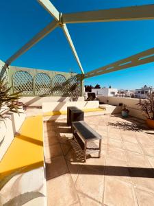 a patio with benches and an umbrella on a roof at Le luxe de Sidi Bou Saïd in Sidi Bou Saïd