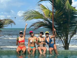 four women in bikinis sitting in the water at the beach at Cosamui Beach House in San Bernardo del Viento