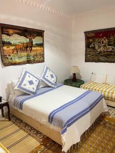 a bedroom with a bed with blue and white pillows at Dar hana in Asilah