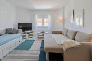 a living room with a couch and a tv at Costa 27 Beach Apartment - By Y Concept in Costa da Caparica