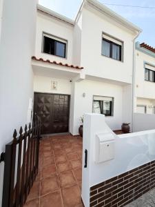 una casa bianca con una porta nera e una recinzione di Moradia São João-Santa Cruz a A dos Cunhados