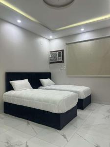 two beds in a room with a projection screen at ملاذ للشقق المفروشة 2 in Tabuk