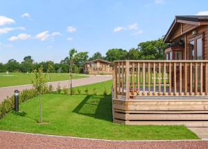 a house with a wooden deck and a yard at York House Holiday Park in Thirsk