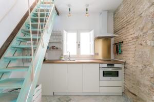een keuken met witte kasten en een ladder bij Fantástico ático en el casco antiguo en a la playa in Cádiz
