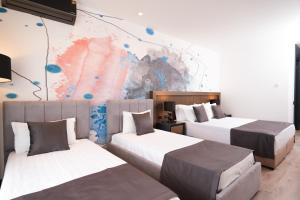 two beds in a room with a mural at Palladium Beach Resort- Luxury Leading Hotels, Private Beach Included in Dhërmi