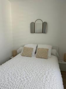 サン・レミ・ド・プロヴァンスにあるAppartement charmant au cœur de Saint-Rémy, idéal pour une escapade provençale !の白いベッド(枕2つ、壁に鏡付)