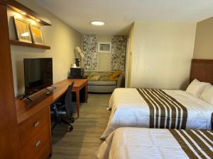a hotel room with two beds and a desk with a television at Princess Motel in Bobcaygeon