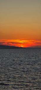an orange sunset over the ocean with the sky at Ithaca in Perdika