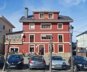 a red building with cars parked in front of it at Casa Rural Nito in Villayón