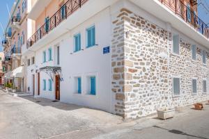a white building with blue windows on a street at Halaris Rooms in Ermoupoli