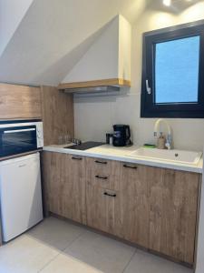 a kitchen with wooden cabinets and a sink and a window at Arch Residence, studio 1, Apothika in Katarráktis