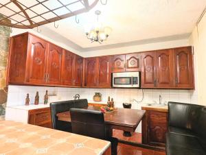 a kitchen with wooden cabinets and a table with chairs at Casa Quetzalli, La Recolección in Antigua Guatemala