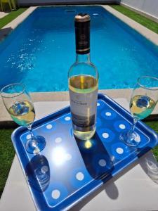 a bottle of wine and two glasses on a tray next to a swimming pool at Meco Beach and Private Pool Villa in Sesimbra