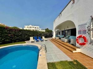 a house with a swimming pool and chairs and a building at Villa OceanKokia in Albufeira
