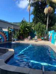 a swimming pool with blue water and palm trees at POUSADA MAORI Boiçucanga in Boicucanga