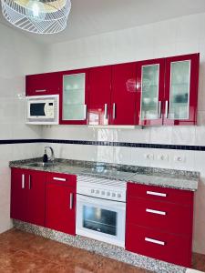 a kitchen with red cabinets and a white stove top oven at Roque`s House A in Telde