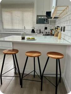 a kitchen with two bar stools and a white counter at 4beds,3 bedrooms,Braai,Full kitchen in Tzaneen