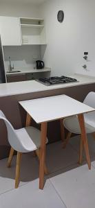 a white kitchen with a white table and chairs at Alquilercipolletti in Cipolletti