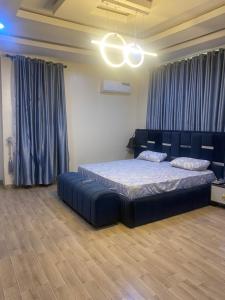 a bedroom with a large bed and blue curtains at 2 bedroom duplex apartment in Ibadan