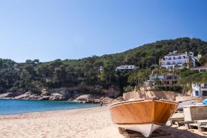 a wooden boat sitting on a sandy beach at Hotel Hostalillo by Escampa Hotels in Tamariu