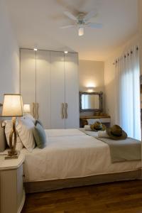 - une chambre avec un grand lit blanc et un ventilateur de plafond dans l'établissement Gatzea Villas, à Kato Gatzea