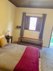 a bedroom with a bed and a window with a bench at Hospedagem Fernandes Cunha, SP in Cunha
