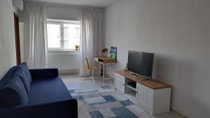 a living room with a blue couch and a tv at Apartament Lara in Constanţa