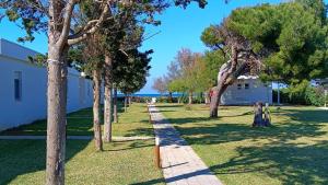 a path through a park with trees and a building at Spiaggiabella Resort in Torre Rinalda