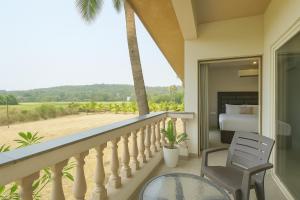 una camera da letto con balcone, letto e sedia di Casa D Village Wing 2 in Goa a Goa