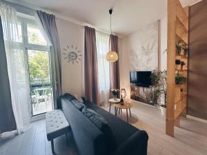 Una sala de estar con un sofá azul y un televisor. en Sophie Apartment, en Toruń