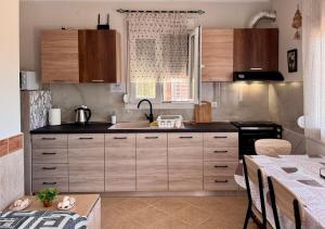 a kitchen with wooden cabinets and a sink and a table at Cottage near the sea in Nea Moudania