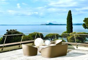 GARDA BLUE HOME on the lake - pool, solarium and garage في توسكولانو ماديرنو: مجموعة كراسي جالسة على شرفة مطلة على الماء