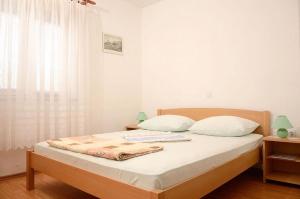 a bedroom with a bed with white sheets and a window at Amalia in Senj