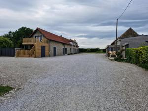 a gravel driveway with a house and a building at Domaine du Bois l'Abbé - La Grange in Saint-Martin-Boulogne