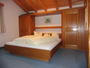 a bed with a wooden headboard in a bedroom at Hotel Garni Elfriede inklusive Super Sommer Card in Serfaus
