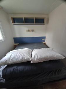 a bed with four pillows on it in a room at mobilhome 232 tohapi marvilla in Torreilles