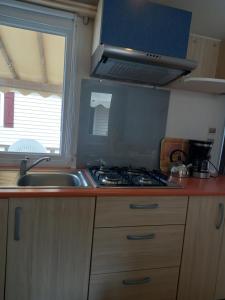 a kitchen with a stove and a sink and a window at mobilhome 232 tohapi marvilla in Torreilles