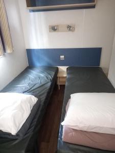 two beds in a small room with a desk and a bed at mobilhome 232 tohapi marvilla in Torreilles