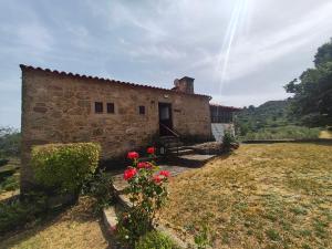 a stone building with a door and some flowers at Quinta de Gonçalo in Guarda